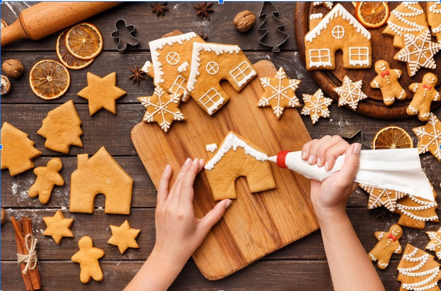 Woman decorating gingerbread cookies with white icing